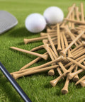 Natural Bamboo Golf Tees Wood Two And Three Quarters Inch And Three And One Quarter Inch Bulk Packs For All Day Practice Tough Tees For Men Women Kids 250 500 1000 2000 Count scattered on green grass beside golf club and balls