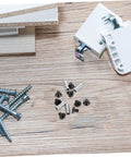 Knife handle rivet and screw repair kit, 4 pieces with metal spacers and black fasteners on wooden surface