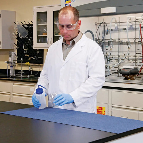 Lab technician with Adhesive-Backed Absorbent Mat For Industrial Floors, Grippy Surface, 16 W X 25 Ft L, Blue, on workstation.