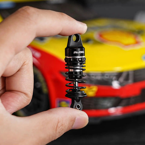 Person holding a 45mm Oil Shock With Progressive Rate Springs for One Twelfth Losi Nascar RC, showing CNC machined aluminum body.
