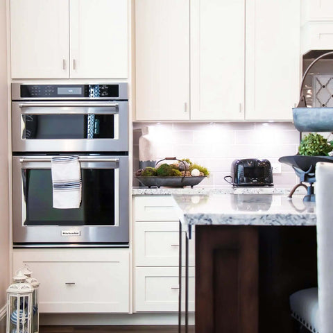 Modern kitchen with stainless steel appliances, including double ovens, elegant countertops, and decorative items.