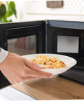 Person placing dish in microwave with 10 Piece Microwave Waveguide Covers Set 5.9 By 4.7 Inches Each Mica Sheet Easy To Cut installed.