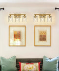 Three Light Vanity Light Fixtures Matte Black Finish With Clear Glass Shades above framed artwork in living room