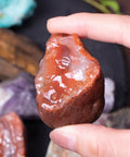 Hand holding a 3 Pound Bulk Rough Madagascar Stones Mix For Tumbling Cabbing And Polishing Natural Raw Crystals