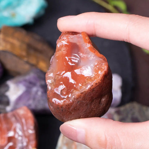 Hand holding a 3 Pound Bulk Rough Madagascar Stones Mix For Tumbling Cabbing And Polishing Natural Raw Crystals