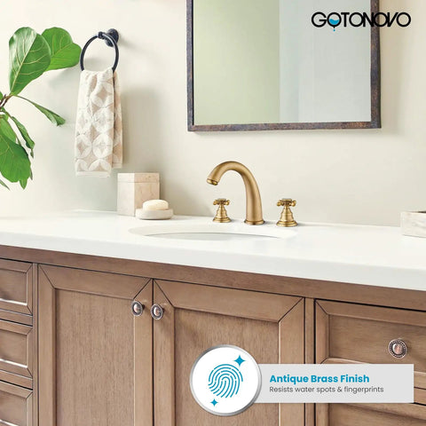 Bathroom vanity with antique brass faucet set, cross handles, and a mirror reflecting the room, highlighting elegant decor.