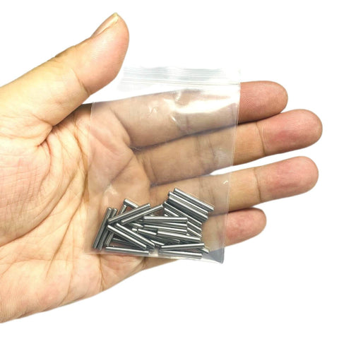 Hand holding a small plastic bag containing a set of 3/32 x 3/4 metal dowel pins, part of the Three Thirty Second Inch By Three Quarter Inch Dowel Pins Set Of Thirty Metal Dowel Pins Shelf Pegs For Shelves Supports Bearings Alloy Steel Wood Bunk Bed Pegs For Furniture Repair.