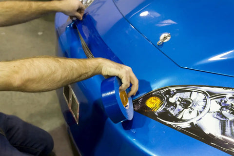 Applying blue duct tape to a blue car bumper for temporary repair or protection; Pro Grade Colored Cloth Duct Tape For Heavy Duty Holding