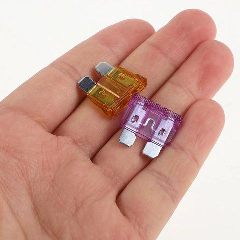 Close-up of hand holding two fuses from 100 Piece Car Fuse Kit With Tester And Puller For Cars Trucks Boats And More DIY Ready For Quick Diagnostics