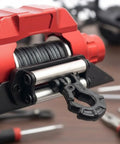 Super Realistic 1/10 Scale RC Truck Electric Winch With Metal Hook And Cable For Crawler Builds Heavy Duty Recovery Gear close-up of red winch with black hook and steel cable.