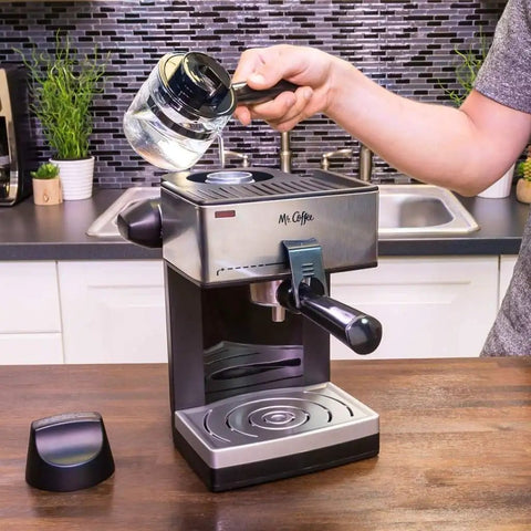 A person adding water to The Real Deal 4 Cup Steam Espresso System With Built In Frothing Arm For Rich Coffee And Creamy Lattes Easy Peasy Setup.