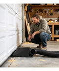 Man examining Straight Flow Under Garage Door Vent With Heavy Duty 6 Inch Duct Adapter for efficient workshop airflow.