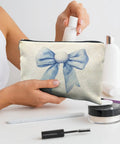 Woman placing a small bottle into a Golf Themed Makeup Bag For Women, Blue Golf Ball Bows Cosmetic Pouch, on a table with cosmetics.