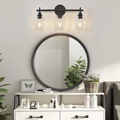 Modern Black Industrial Three Light Vanity Light With Wine Glass Shades in a bathroom over a round mirror and vanity