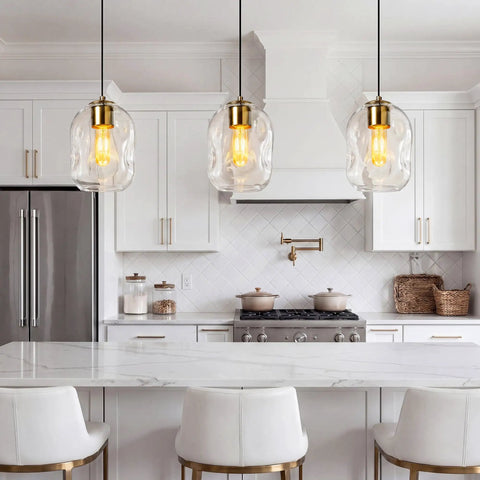 3 Pack Gold Pendant Lights For Kitchen Island Featuring 8.7 Inch Hand Blown Clear Art Glass Globes above a marble countertop.