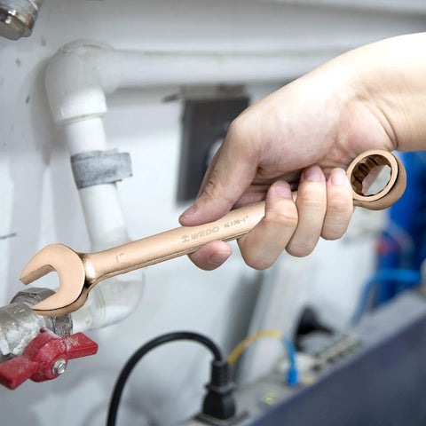 Hand using beryllium copper wrench from Non-Sparking Tools Set 37-Piece Pro Grade Spark Free Safety Kit, tightens pipe fitting.