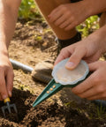 Person using Handheld Seed Planter and Spreader for Lawn and Garden, Adjustable Five Setting Seeder Tool in outdoor soil.