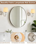 1-Light Brushed Nickel Vanity Light with Beige Fabric, Modern Wall Sconce beside a round mirror, featuring crystal details.