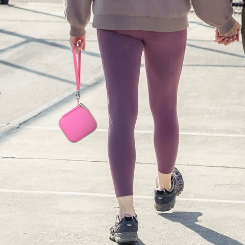 Tough Love Hardshell Travel Case For Magnetic Foldable 3 In 1 Chargers held by a person in pink leggings, perfect for secure storage.