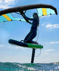 Person using inflatable surfboard for windsurfing and wing surfing with totally portable handheld foil wing kite for water sports.