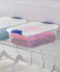 Four Pack 15 Quart Storage Bins With Hella Sturdy Snap Tops And Crystal Clear Lids Stackable Plastic Totes on a wire shelf with folded clothes.