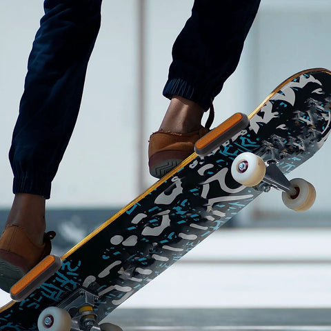Skateboard close-up with vibrant graffiti design and rubber grips being used in skate trick performance.