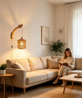 ZEORIVAX Rattan Wall Lamp with Plug-in Cord Hand Woven Paper Rope Sconce glowing beside a woman reading on a beige couch.