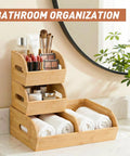Three tier stackable bamboo organizer with toiletries and rolled towels on marble countertop