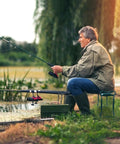 Man sitting on Garden Kneeler And Seat Foldable Bench With Soft Cushion Pad For Outdoor Gardening And Fishing Dual Function Kneeler Converts To Sit Stand Stool Heavy Duty Iron Frame Portable And Easy To Use Green by a pond fishing.