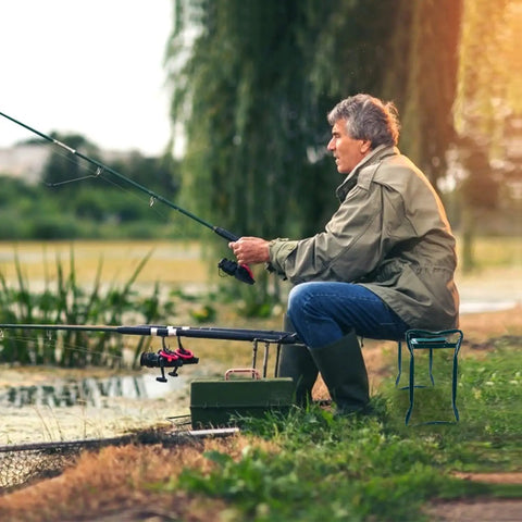 Man sitting on Garden Kneeler And Seat Foldable Bench With Soft Cushion Pad For Outdoor Gardening And Fishing Dual Function Kneeler Converts To Sit Stand Stool Heavy Duty Iron Frame Portable And Easy To Use Green by a pond fishing.