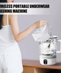 User adding white underwear to the Straight Fire Cordless Mini Washing Machine Portable Underwear Cleaner on a wooden surface.