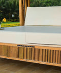 Bamboo outdoor swing seat with white cushions in a garden setting