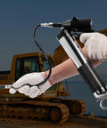 Person using 6000 PSI Air Powered Grease Gun For Heavy Duty Lubrication, 14 oz load, 18.5 inch flexible hose near construction vehicle.