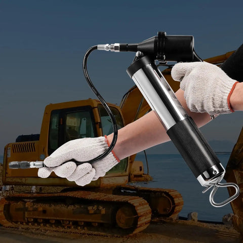 Person using 6000 PSI Air Powered Grease Gun For Heavy Duty Lubrication, 14 oz load, 18.5 inch flexible hose near construction vehicle.