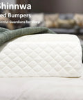 Close-up of quilted white memory foam bed bumper for toddlers with a soft edge safety rail and green blanket on bed.