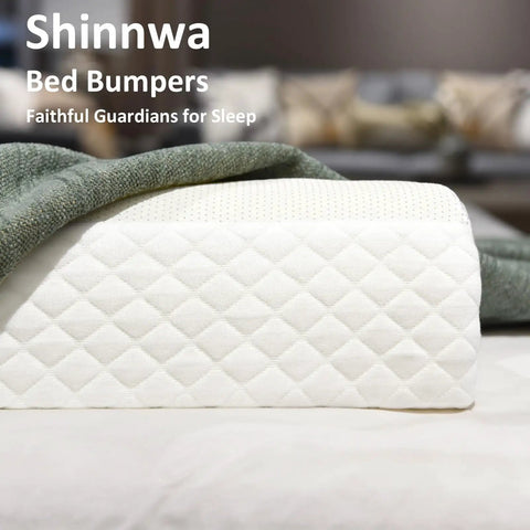 Close-up of quilted white memory foam bed bumper for toddlers with a soft edge safety rail and green blanket on bed.