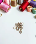 150 Piece Mini Buckle Set For Doll Clothes And Craft Projects, Small Belt Fasteners For DIY Sewing, Alloy Buckles In Silver, Gunmetal, And Antique Copper Colors For Model Miniatures And Craft Accessories surrounded by colorful threads.