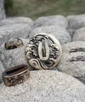 Antique Copper Tsuba And Fuchi Kashira Menuki Set For Samurai Sword Koshirae displayed on stones, detailed Japanese ornament