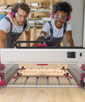 Two people using All-In-One 3 Axis CNC Router Kit Maker-Friendly With Custom 710W Spindle, 7000 To 30000 RPM for engraving wood.
