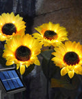 Upgraded 4 Flower Solar Sunflowers With Fairy Light Petals For Yard Decor, glowing in garden with solar panel base.