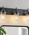 Matte Black 3 Light Vanity Wall Sconce With Clear Glass Shades For Bathroom Bedroom Hallway Or Kitchen Dope Farmhouse Style Lighting Fixture That Elevates Any Space And Sets The Mood, shown above a mirror with bright bulbs.