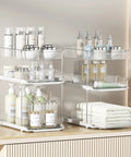 Total Game Changer Clear Three Tier Under Sink Organizer Two Pack showcasing stacked bins with beauty products and towels.
