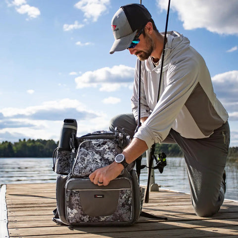 Angler on dock with Heavy Duty Fishing Backpack With 2 Rod Holders 4 Tackle Boxes And Rain Cover Built From 1200D Water Resistant Nylon