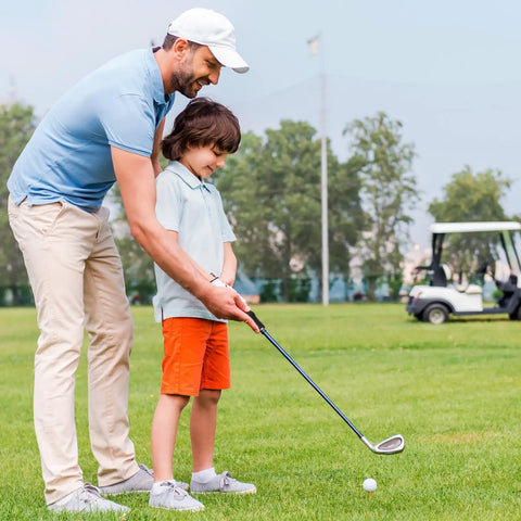 Adult teaching child to swing on golf course with a focus on Three Pack Golf Grip Trainer Set For Right Handed Golfers Easy Swing Trainer Accessories To Boost Your Grip Build Muscle Memory And Correct Hand Position For Consistent Controlled Swings.