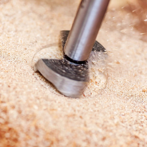 Forstner drill bit, gray metal, woodworking tool drilling into wood close-up