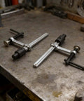 Two Pack Beefy Metal Hold Down Clamps For Woodworking 16mm Dog Hole Bench Clips With Ergonomic Handle on a workbench