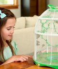 Girl observing butterflies in the Butterfly Farm Live Habitat Kit For Kids Watch Caterpillars Turn Into Butterflies STEM Toy on table.