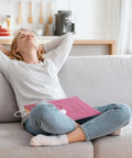 Woman relaxing on a couch with Top Shelf Peach Pink Flannel Heating Pad Replacement Cover For 12X24 Inch Electric Heat Packs.