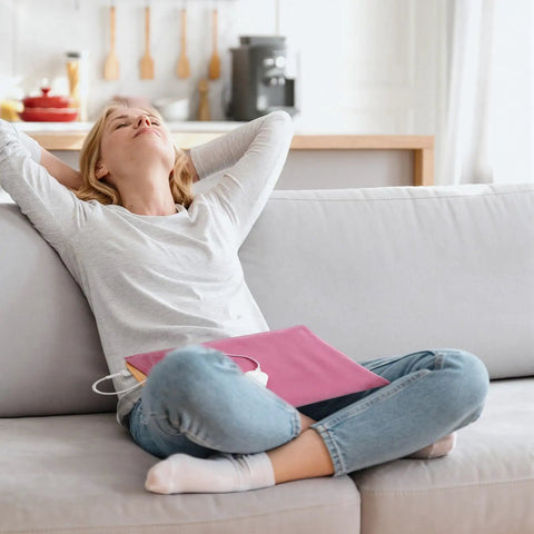 Woman relaxing on a couch with Top Shelf Peach Pink Flannel Heating Pad Replacement Cover For 12X24 Inch Electric Heat Packs.