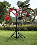 Red bike on Pro Grade Bike Repair Stand For Road And Mountain Bikes With Four Leg Stability Telescoping Arm Quick Release Tool Tray